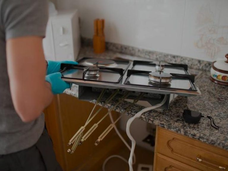 Technician repairing a gas cooktop in a home kitchen
